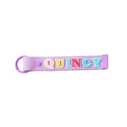 Le Petit Society's purple bag tag personalised with name patches.