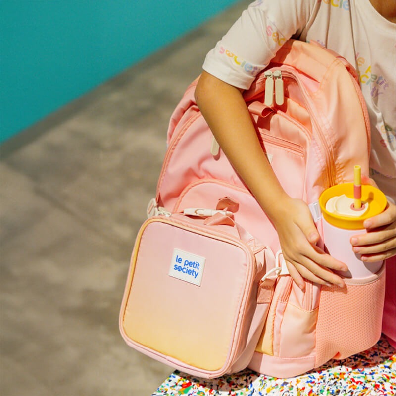 A close up of the LPS kids double pocket school bag in an ombre pink and yellow design.