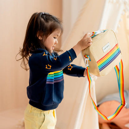 A toddler with a thermal rainbow lunch bag from Le Petit Society.