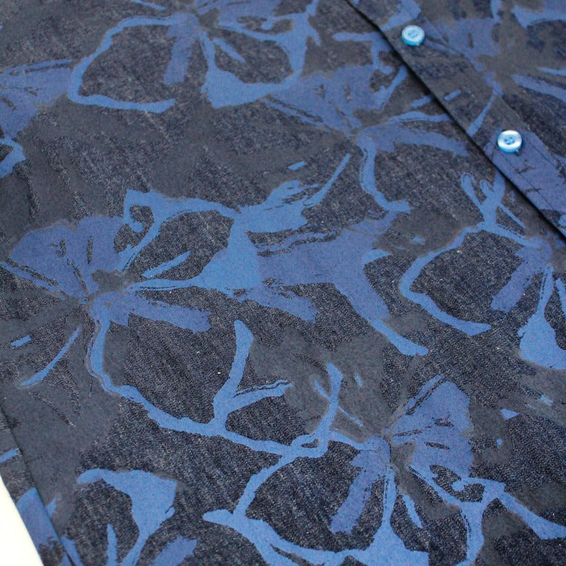 Close-up of the navy blue chambray fabric from the Le Petit Society x Sheila Sim CNY 2026 collection, showing the tonal floral horse print in layered shades of blue. The texture of the woven chambray material is visible beneath the print.