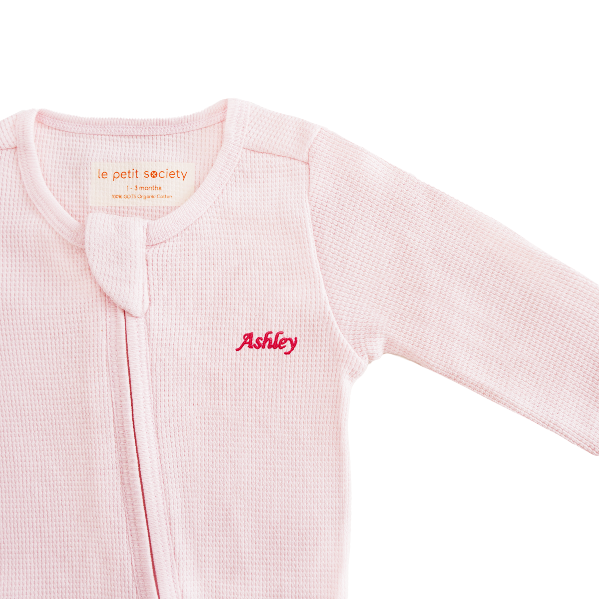 An organic baby zip sleepsuit in pink with a name embroidery personalisation, by Le Petit Society.