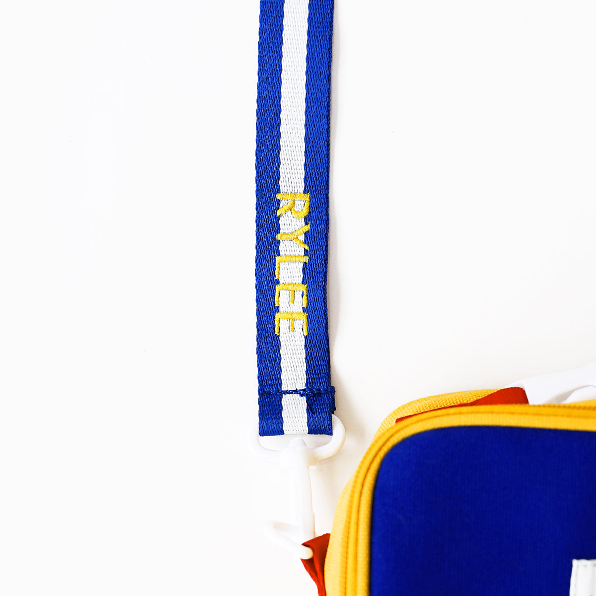 A close up of a personalised name embroidery on a blue and white strap of a thermal lunch bag from Le Petit Society.