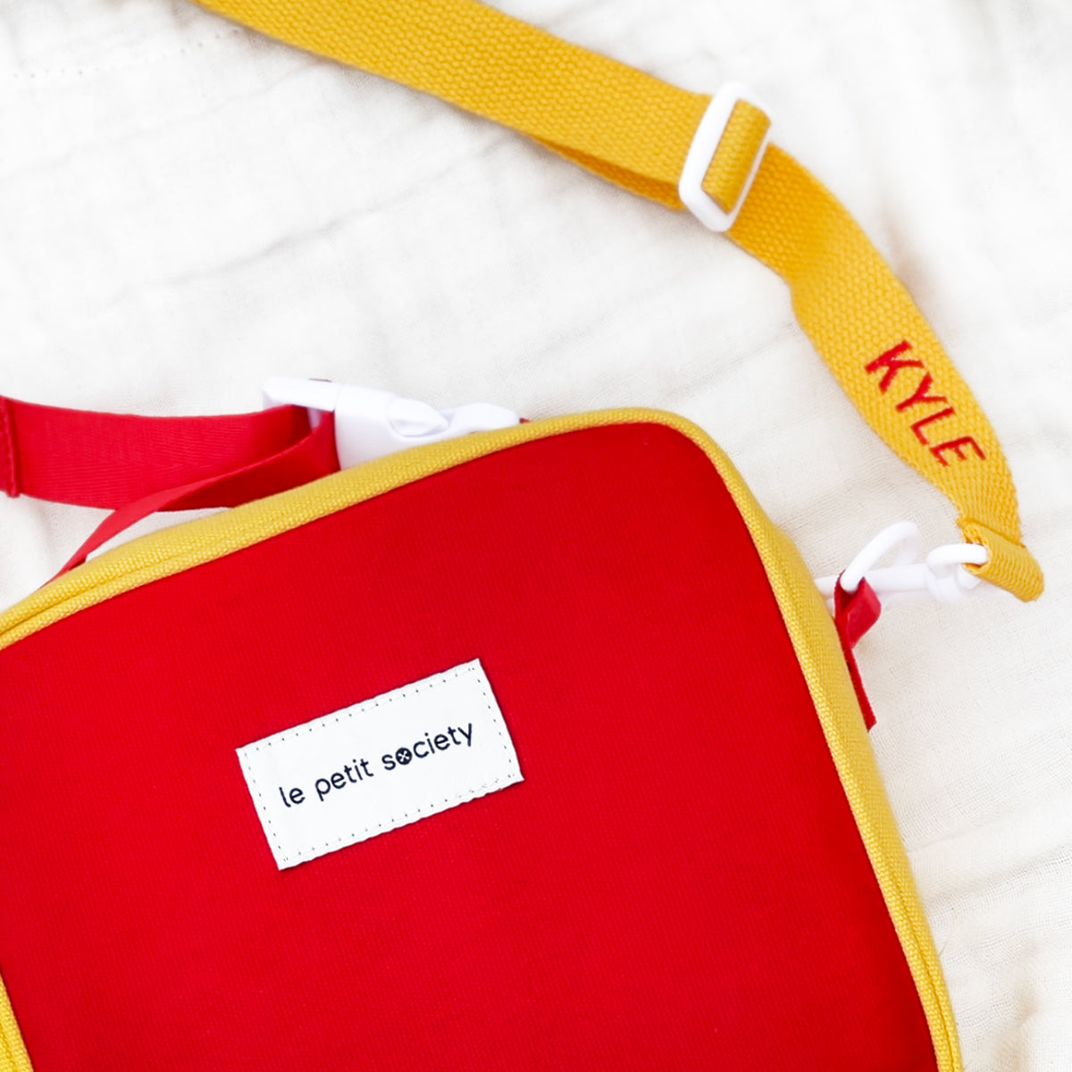 A close-up of a personalised name embroidery on the strap of a thermal lunch bag from Le Petit Society.
