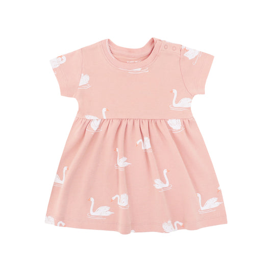A peach-coloured, girl's organic dress adorned with a print of swans from Le Petit Society.