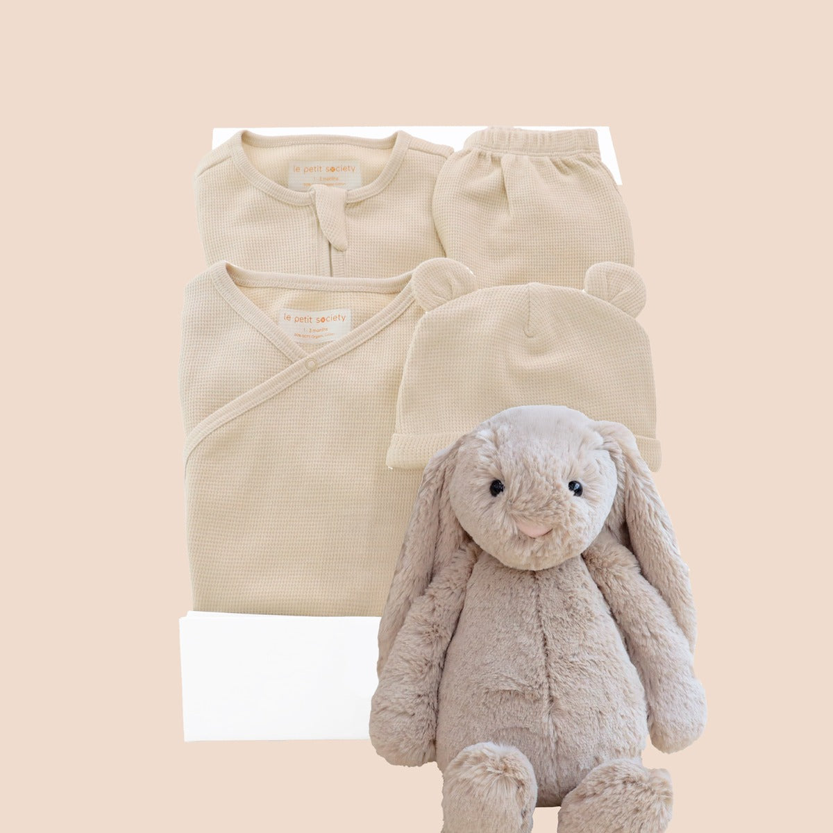 A baby welcome gift set in mocha brown by Le Petit Society, consisting of an organic baby essentials set in beige, a beige bunny by Jellycat and a signature gift box.