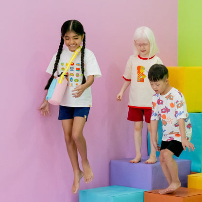 Three kids at play while wearing graphic tees from Le Petit Society.
