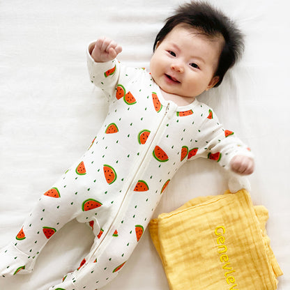 A baby wearing Le Petit Society's organic zip sleepsuit in watermelon print.