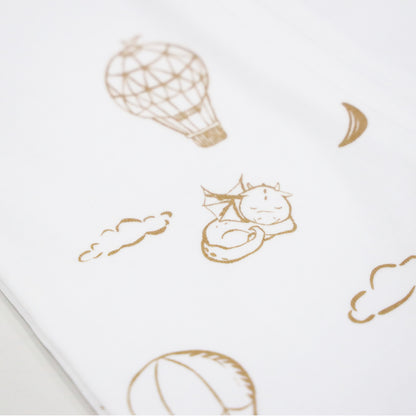 A close-up of the print of Le Petit Society's baby organic zip sleepsuit in dreamy dragon print, which consists of  sleeping dragons, crescent moons, clouds and hot air balloons.