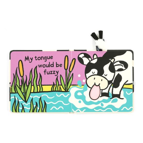 Open children's book showing a cartoon black and white calf drinking from blue water with text “My tongue would be fuzzy.” Includes soft textured pink tongue and fabric black and white ears on the top right.