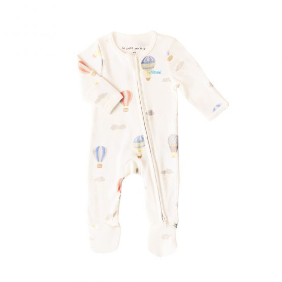 An organic baby zip sleepsuit from Le Petit Society. It is beige in colour with a print of hot air balloons and foldable mittens and footies.