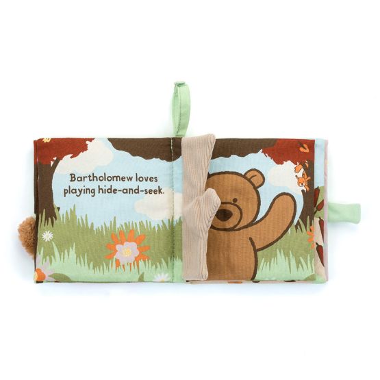 An open fabric baby book shows Bartholomew Bear peeking from behind a soft, plush tree. The page reads: 