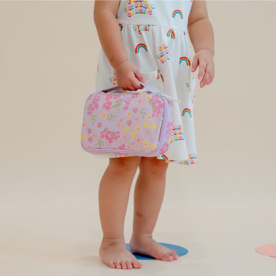 A toddler carrying a purple explorer pencil case and pouch with a floral print.