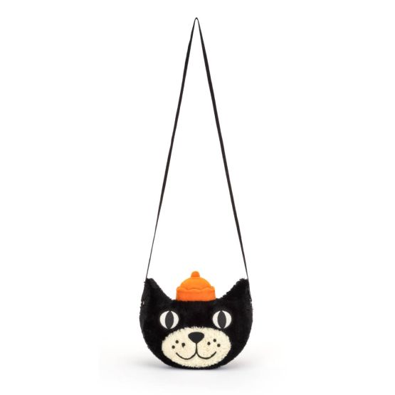 A front view of a plush black cat crossbody bag with embroidered eyes, smiling cream-colored face, soft orange hat on top and a long black strap hanging straight down.